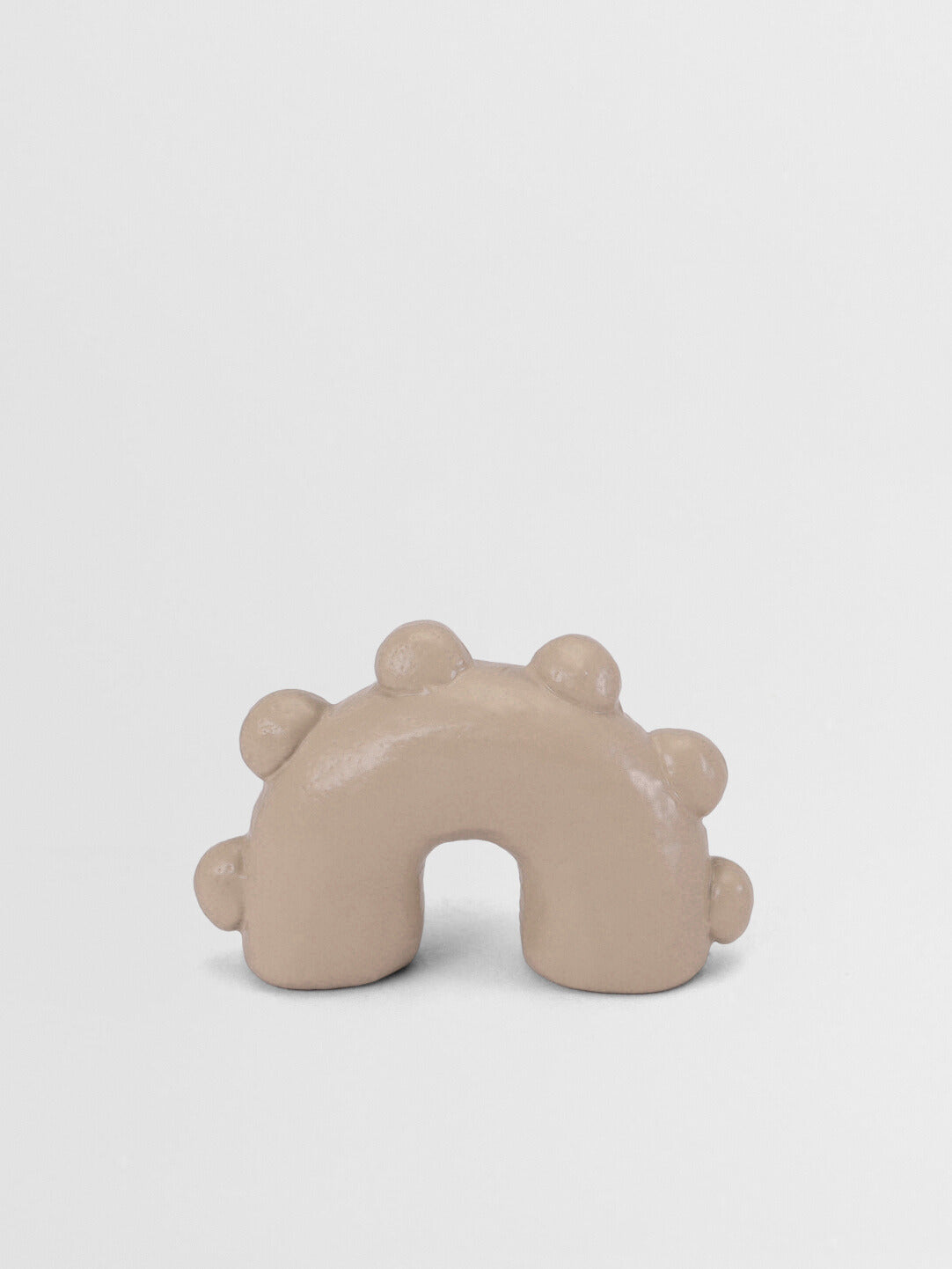 Beige arch-shaped pull knob on a light gray background