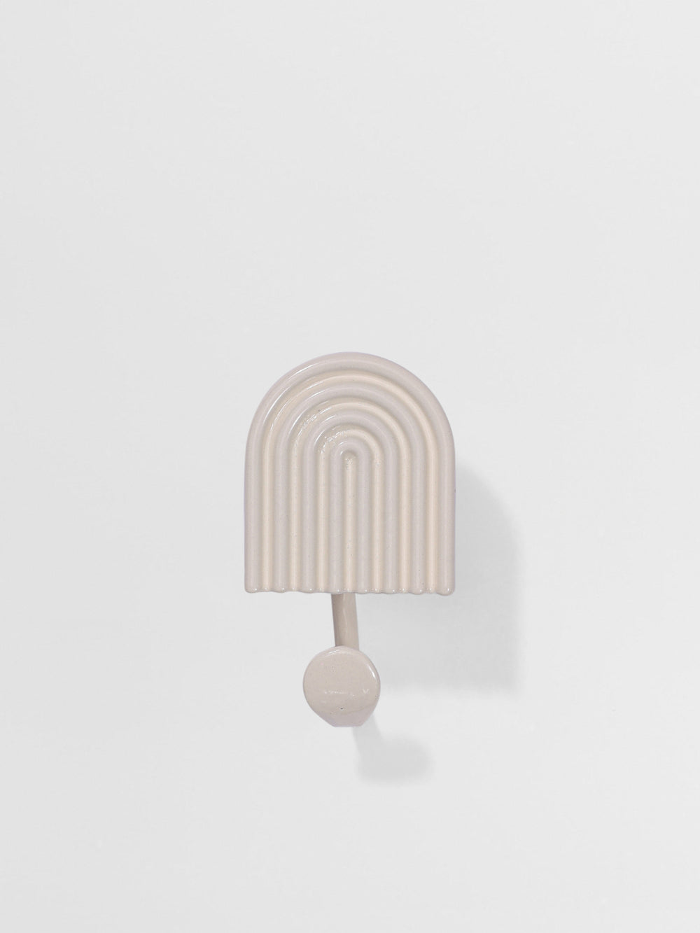 Decorative white wall hook with arch design on a light gray background