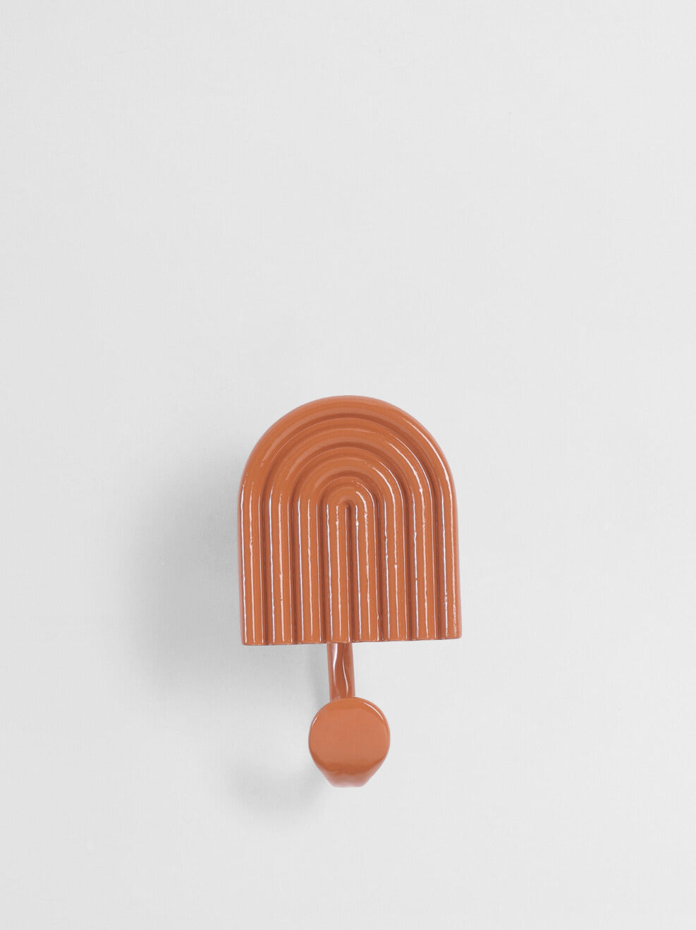 Orange arch-shaped wall hook on a light gray background