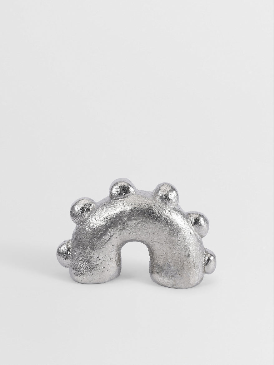 Silver nickel jewelry piece on a light gray background