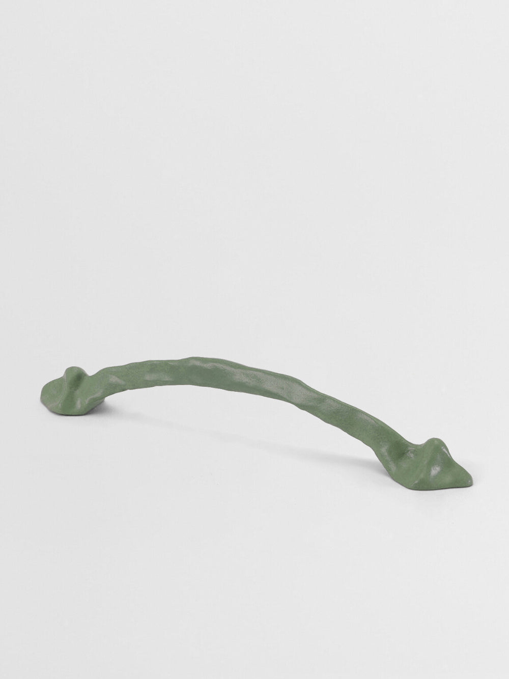 Decorative sage green cabinet handle on a light gray background