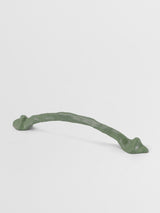 Decorative sage green cabinet handle on a light gray background