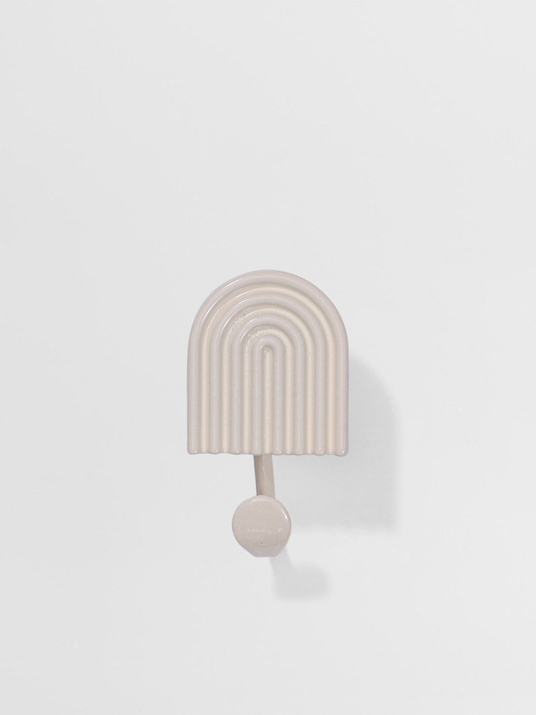 Decorative white wall hook with arch design on a light gray background